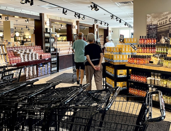 DeLallo Italian Marketplace with black shopping carts, a couple shopping and lots of boxes bottles and jars on display.