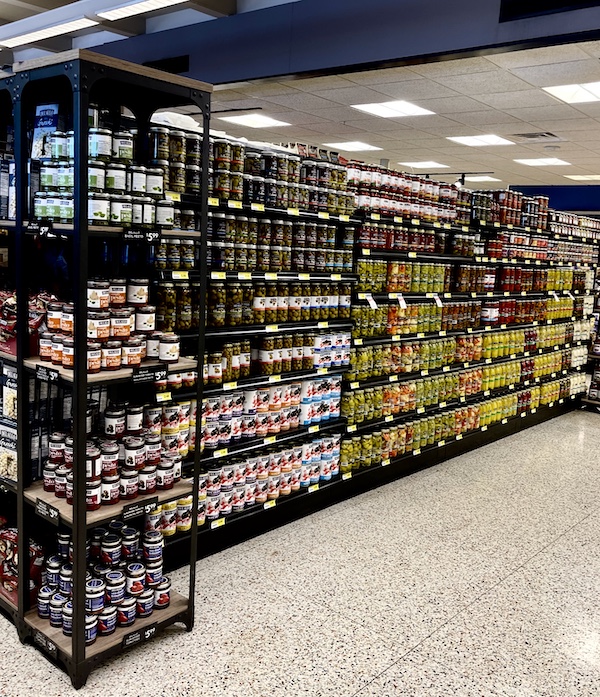 DeLallo Italian Marketplace aisle with shelves filled with jars of pickles and olives.