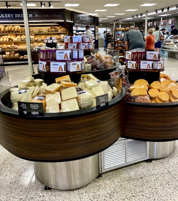 DeLallo Italian Marketplace round displays of cheese in foreground, breads in background
