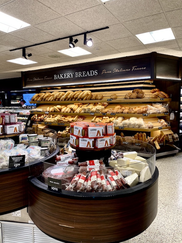 DeLallo Italian Marketplace round displays of salami and cheese with wall of breads in the background