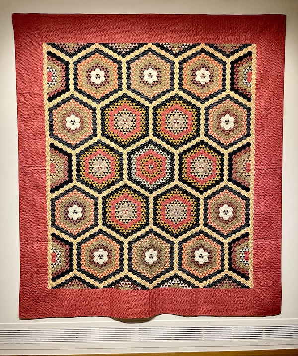 Red, gold and black quilt with hexagon patterns and red border at Allentown Art Museum Quilts