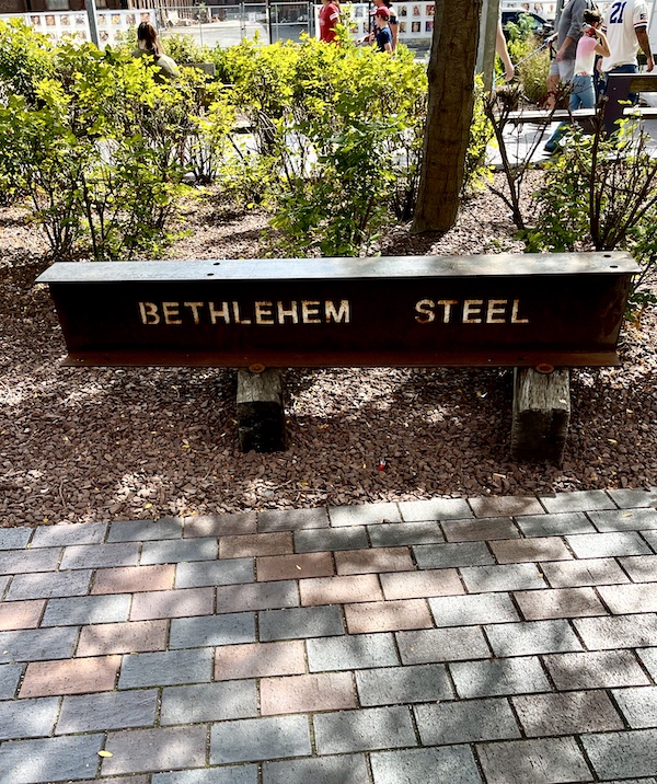 Marble bench with Bethlehem Steel etched on side against a backdrop of bushes at Bethlehem Steel Stacks