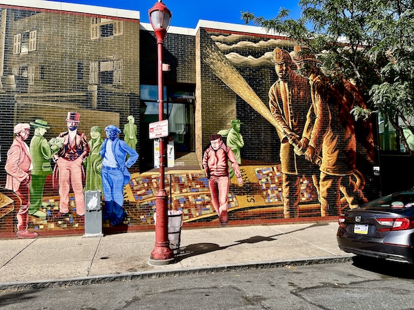 Painting on brown brick building depicting people throughout Philadelphia history is another example of the Murals Around Philadelphia