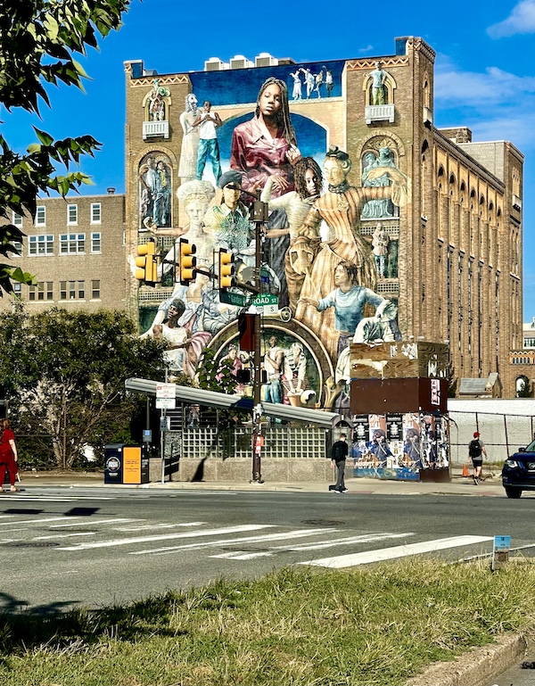 Colorful mural painted on the front of a building depicting men and women through the years to present day. Beautiful example of the Murals Around Philadelphia