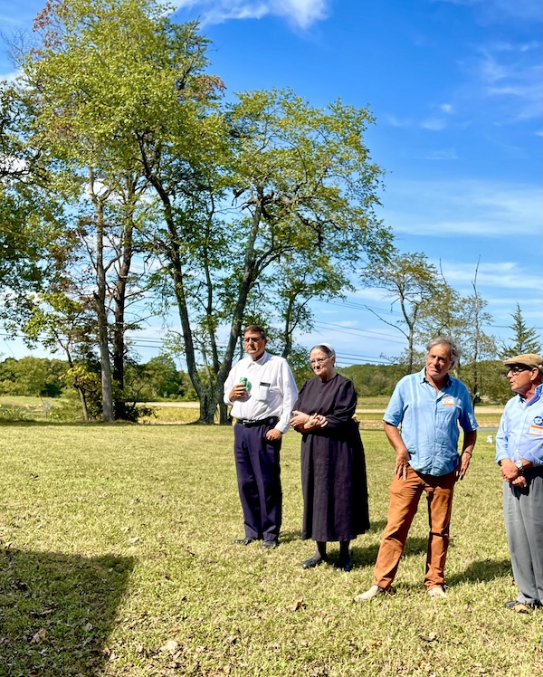Three men and a woman on a lawn with trees in the background at Alliance Colony Pittsgrove NJ