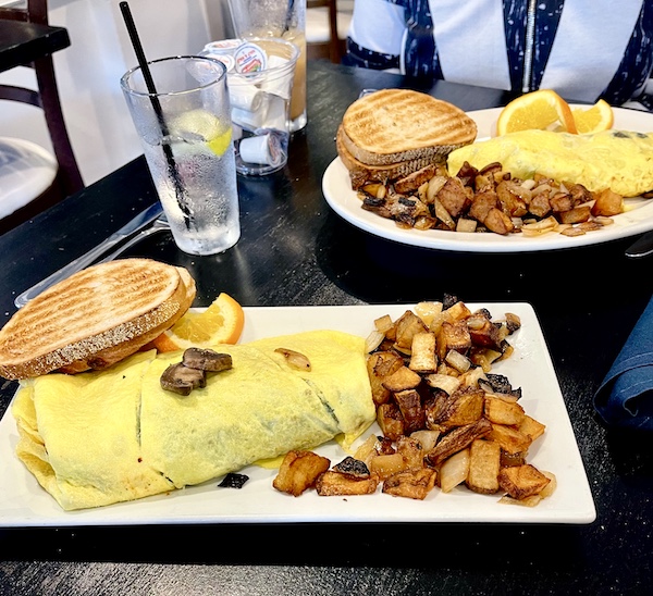 White rectangular plate topped with and omelette with home fries and rye toast at Johnny's Café Margate NJ