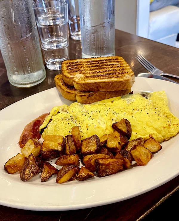 Oval plate topped with and omelette home fries and sour dough toast at Johnny's Café Margate NJ