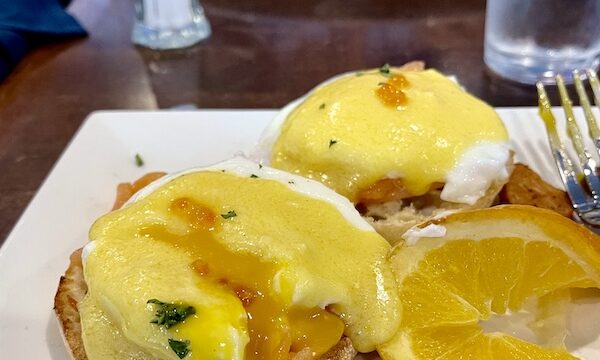 Poached egg cut into to reveal runny yolk, orange slice garnish at Johnny's Café Margate NJ
