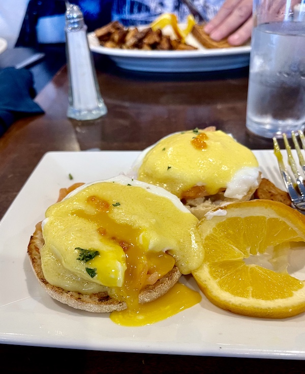 Poached egg cut into to reveal runny yolk, orange slice garnish at Johnny's Café Margate NJ