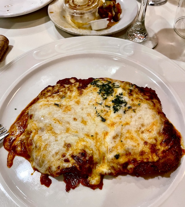 White plate topped with large veal cutlet, tomato sauce and melted cheese at Sapore Woodfire Pizza and Restaurant