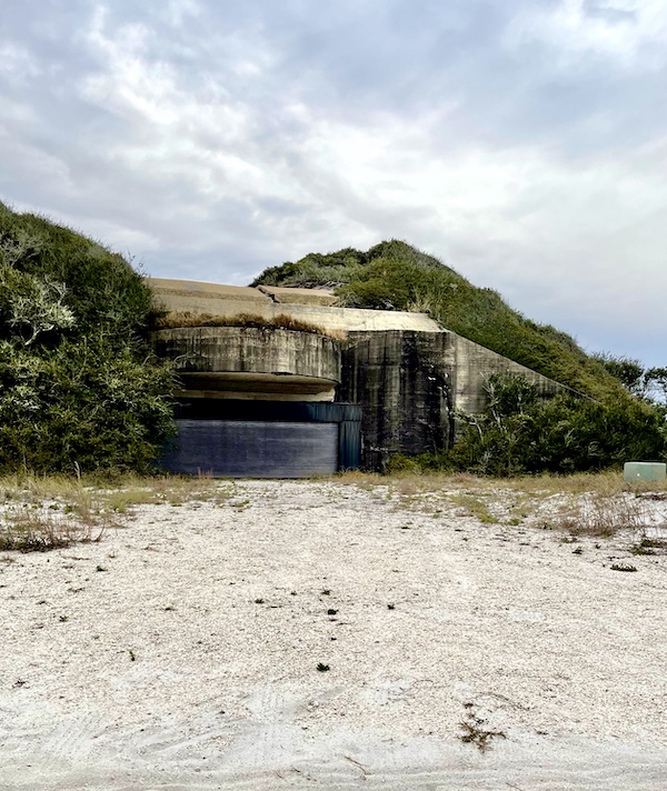 Concrete bunker hidden by trees and bushes with sand in front at Fort Pickens Pensacola Florida