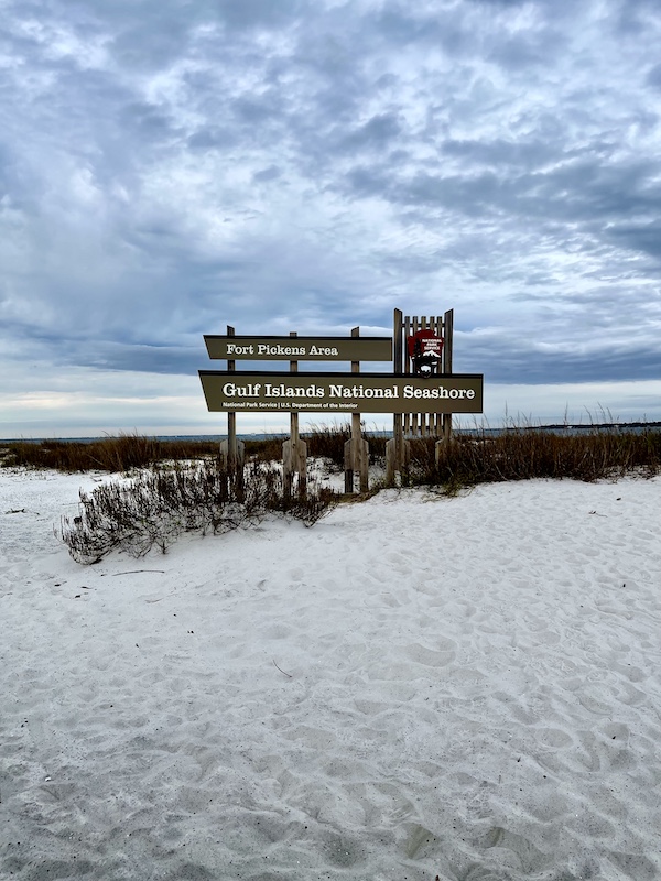 National Seashore sign in beach grasses on the sand with gulf in view. Part of Fort Pickens Pensacola Florida