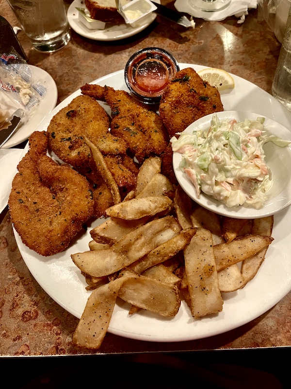 White dinner plate topped with a pile of golden brown fried shrimp a dish of coleslaw and french fries was part of our October Fun at Jersey Shore
