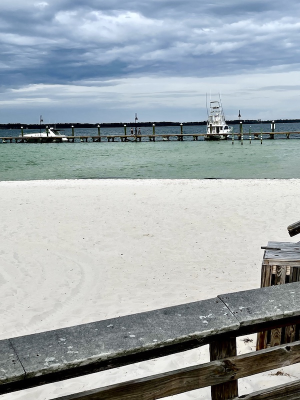 View of the Pensacola Beach and Boardwalk with boats floating in the Gulf of Mexico.