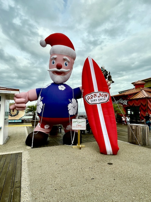 Giant blow up Santa in a wet suit with a surfboard and Santa hat at Pensacola Beach and Boardwalk