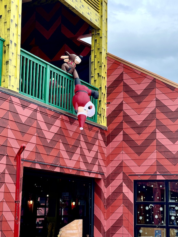 Blowup reindeer holding a blowup Santa upside down by the foot from a balcony at Pensacola Beach and Boardwalk