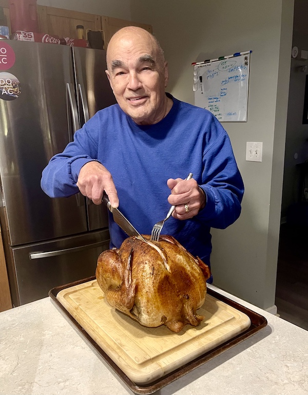 Steve, in a blue sweatshirt, carving the Thanksgiving turkey.