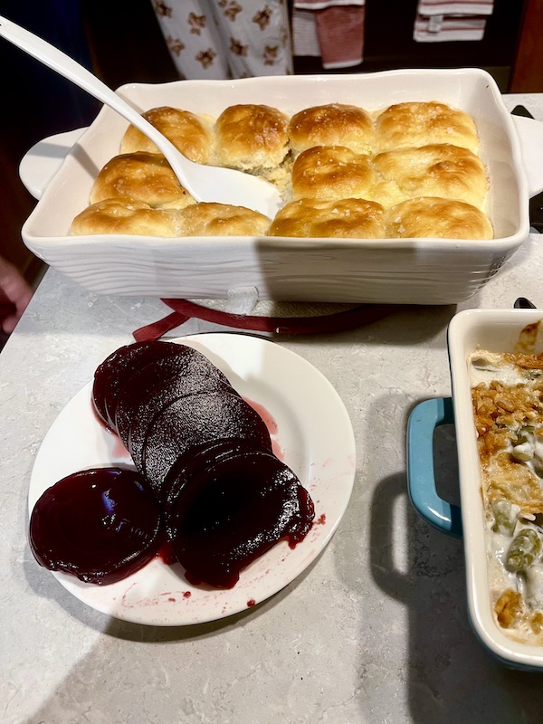 Buffet set with plate of sliced cranberry sauce and baking dish filled with golden brown rolls for our Thanksgiving in March?