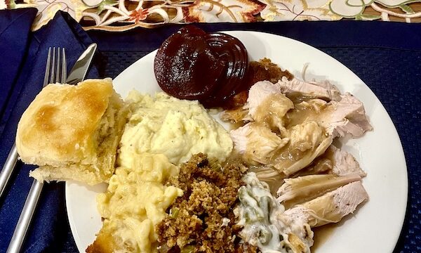 White dinner plate topped with sliced turkey, gravy, stuffing, mac and cheese, mashed potatoes, green bean casserole, rolls and cranberry sauce for our Thanksgiving in March?