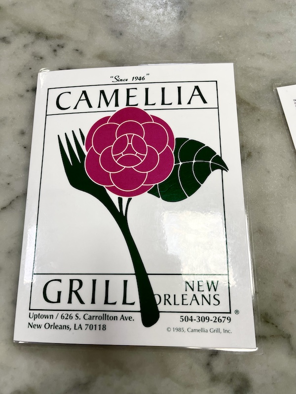 White menu with single stem red camellia and a fork on the cover at Camellia Grill New Orleans