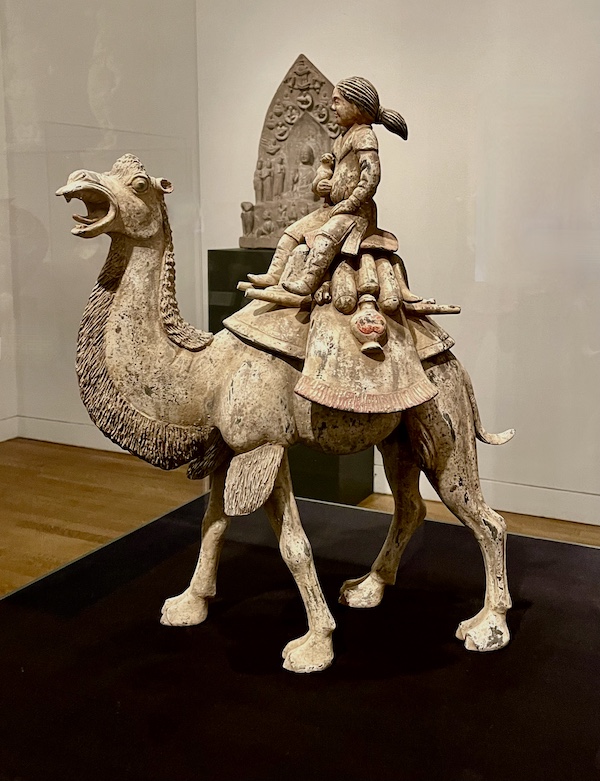 Earthenware figure of a camel with a rider that's holding a small animal on display at the New Orleans Museum of Art