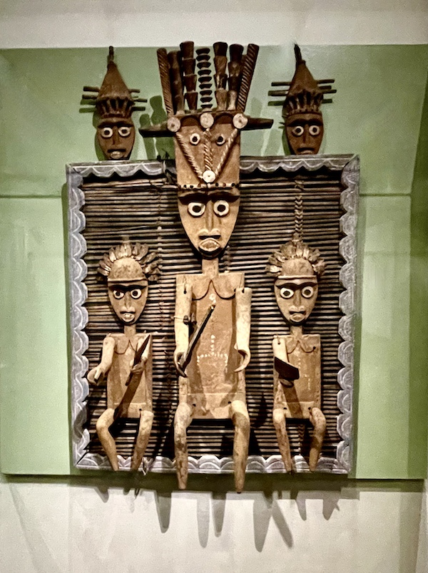 Carved wood screen with primitive figures on display at New Orleans Museum of Art
