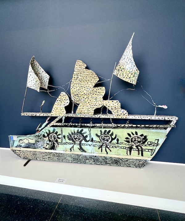 Sculptural art piece of a slave ship showing men with chains and colorful sails at the New Orleans Museum of Art