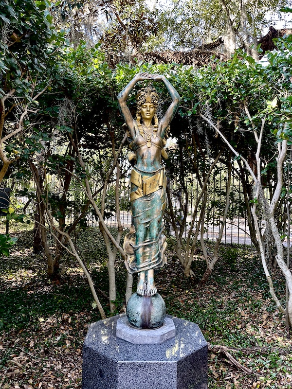 Colorful statue of a woman with arms above her head, hands touching in art deco style. Photo taken while Sharing Sculpture Garden with Friends