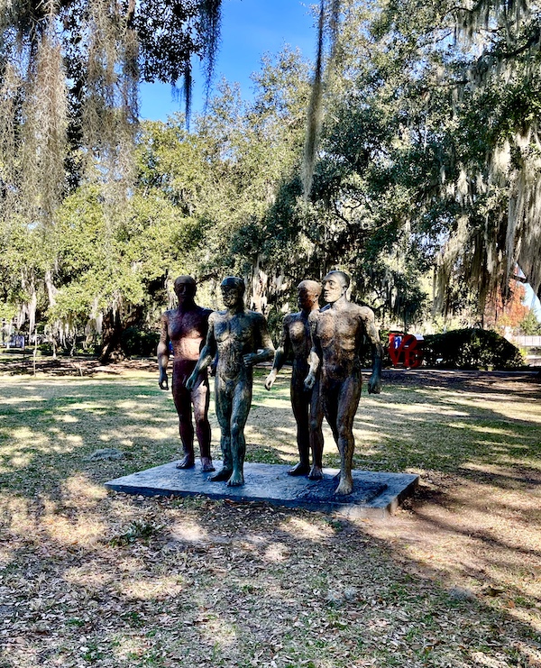 Rustic sculpture of 4 warriors standing among the trees seen while Sharing Sculpture Garden with Friends