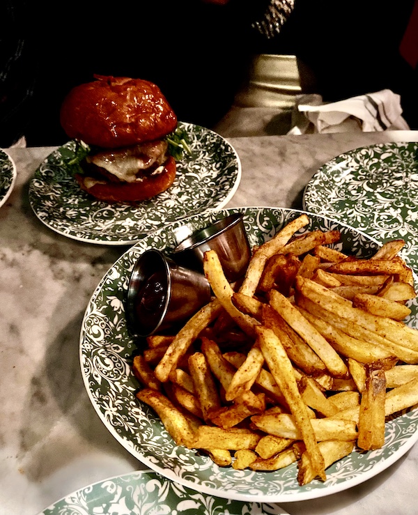 Big plate of Cajun spiced French fries with burger in background at The Columns New Orleans