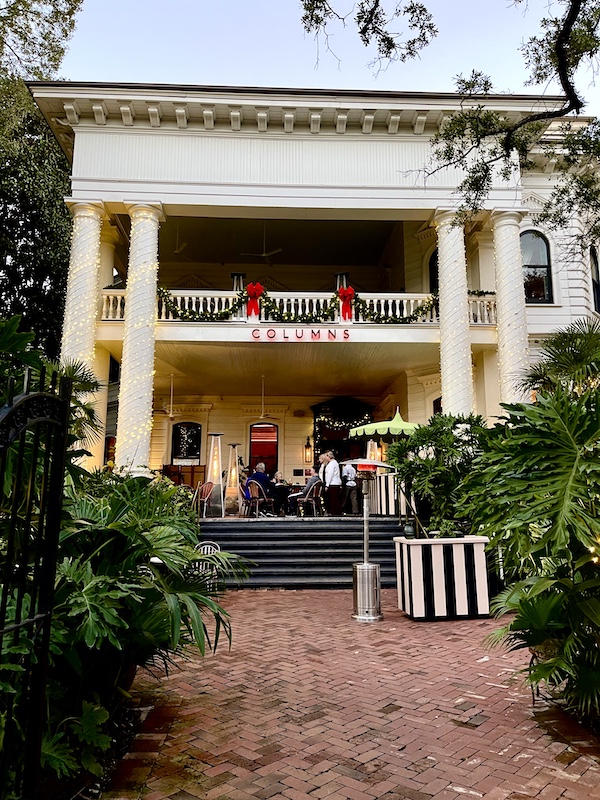 Historic Columns hotel is a white building with huge covered and uncovered patio for drinks and dining.