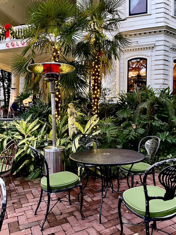 Tropical landscaping and portable torch heater by wrought iron table and chairs at The Columns New Orleans