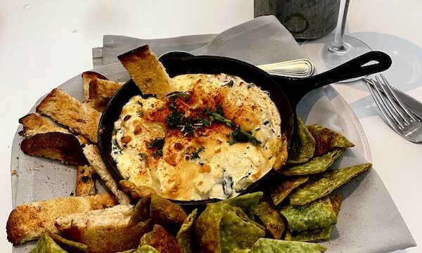 Cast iron skillet filled with warm creamy dip and surrounded by garlic toasts and green tortilla chips at The Vault Tulsa Oklahoma