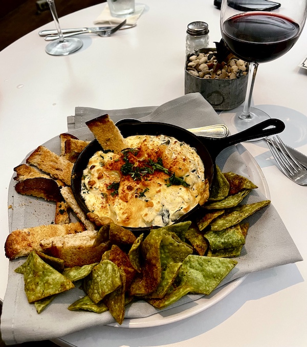 Cast iron skillet filled with warm creamy dip and surrounded by garlic toasts and green tortilla chips at The Vault Tulsa Oklahoma
