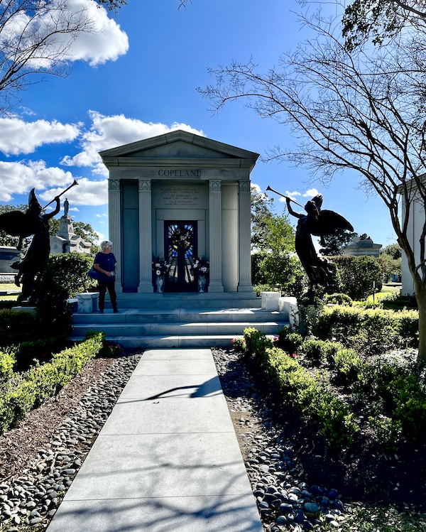 Greek style mausoleum with columns and bronze herald angels on each side at Historic Metairie Cemetery Louisiana