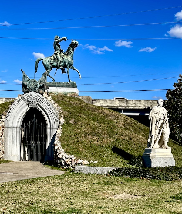 Arch with bronze statue of a civil war hero on horseback sits atop a small mound another statue of a soldier is beside it at Historic Metairie Cemetery Louisiana