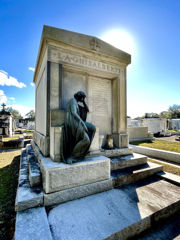 Mausoleum with bronze statue of a woman sitting on the step, head in hand at Historic Metairie Cemetery Louisiana