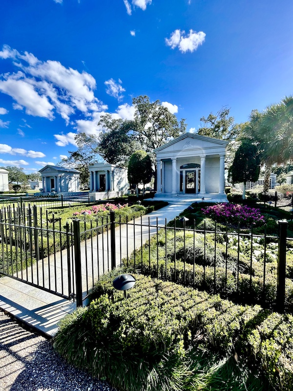 Small mausoleum with garden and black wrought iron fence at Historic Metairie Cemetery Louisiana