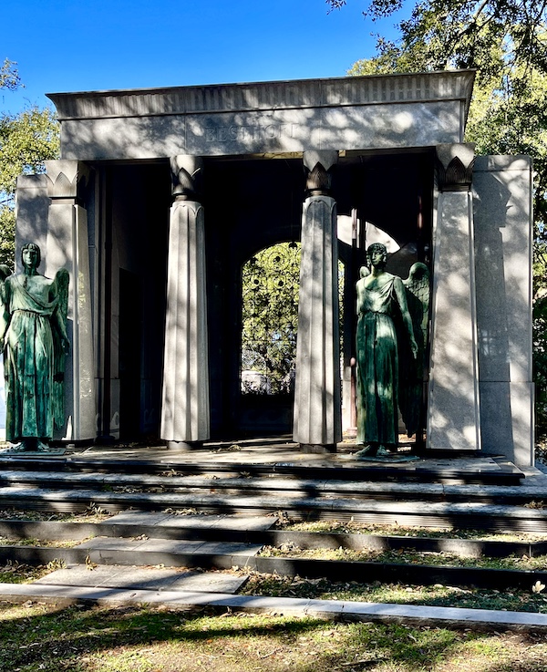 Greek columns of memorial flanked by verde gris bronze angels at Historic Metairie Cemetery Louisiana