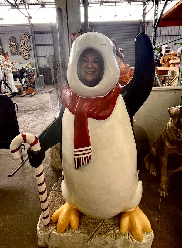 Me with my face showing through the dancing penguin sculpture at Mardi Gras World NOLA