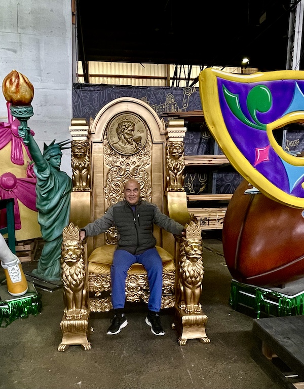 Steve sitting on a huge gold throne sculpture at Mardi Gras World NOLA