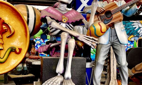 Mexican skeleton sculpture alongside one of Elvis Presley with a guitar at Mardi Gras World NOLA