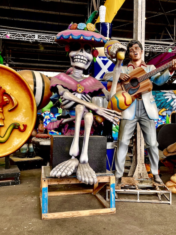 Mexican skeleton sculpture alongside one of Elvis Presley with a guitar at Mardi Gras World NOLA