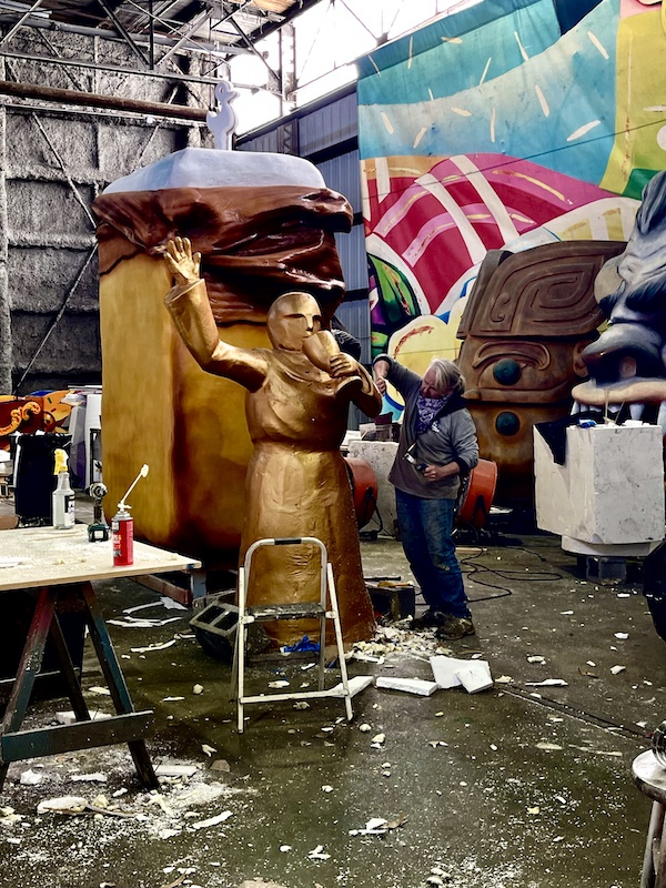 Gold statue of a man in a toga with a goblet being painted at Mardi Gras World NOLA