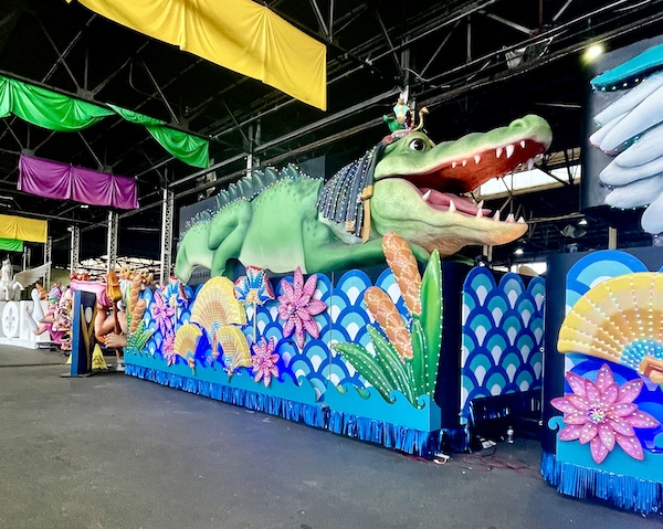 Float with giant alligator atop and colorful skirt hiding the wheels at Mardi Gras World NOLA