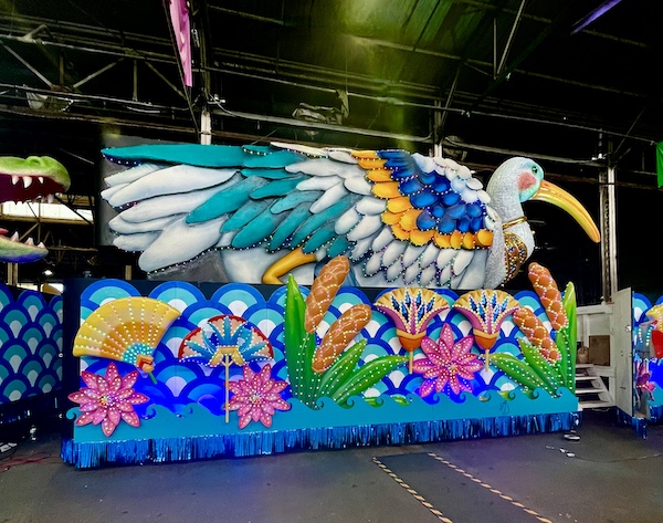 Float with giant bird atop and colorful skirt hiding the wheels at Mardi Gras World NOLA
