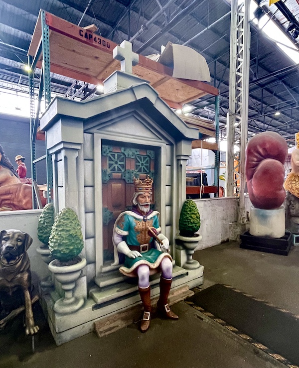 Sculpture of a small building with a king sitting on the front step at Mardi Gras World NOLA