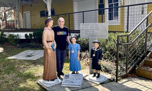 Steve standing among statues of a woman and two children in front of a building in Le Vieux Village Opelousas LA