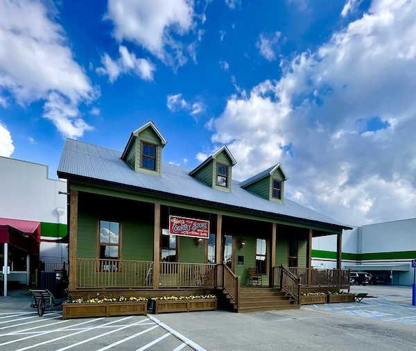 Dark green and wood building with covered porch and 3 dormer windows is the country store of Tony Chachere's Famous Creole Seasoning