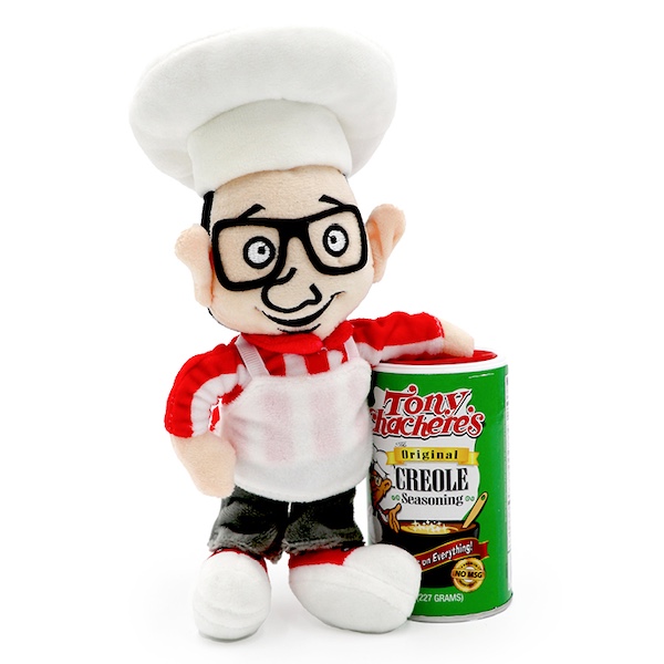 Soft sculpture doll of a male chef with black rimmed glasses and arm resting on a can of Original Creole seasoning from Tony Chachere's Famous Creole Seasoning